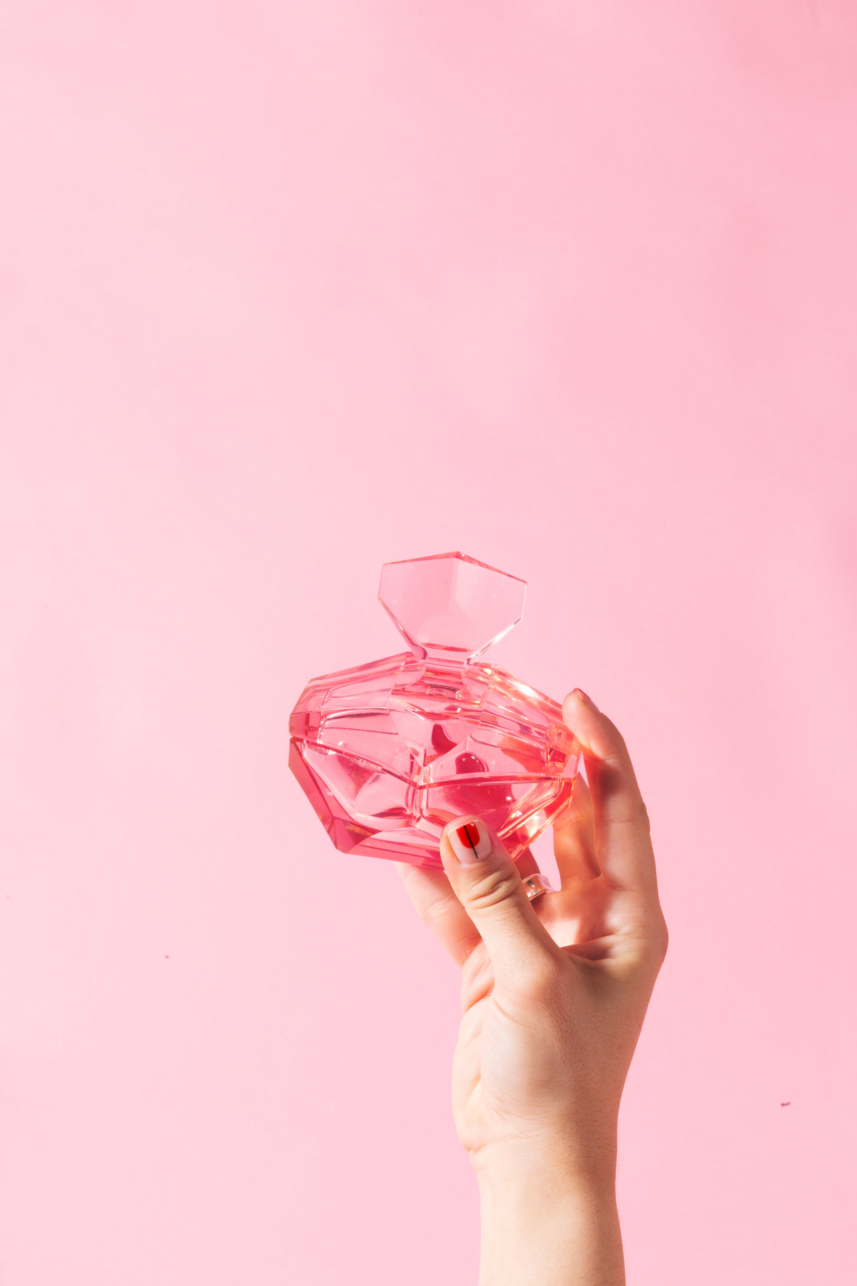 hand-holds-pink-glass-bottle-against-pink.jpg